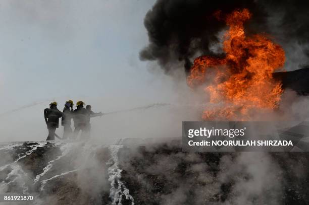 Afghan firefighters attempt to extinguish a burning fuel tanker which was exploded by a magnetic bomb on the outskirts of Jalalabad, on October 16,...