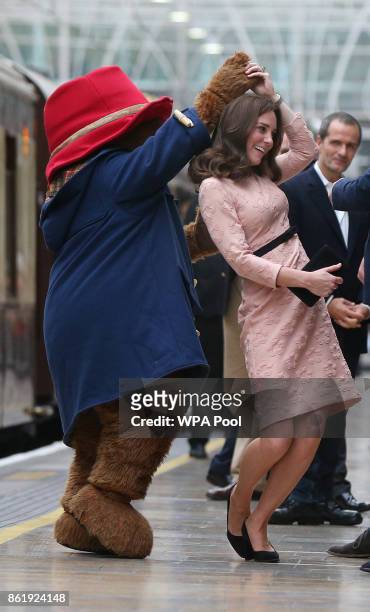 Catherine, Duchess of Cambridge dances with Paddington bear on platform 1 at Paddington Station as she meets the cast and crew from the forthcoming...