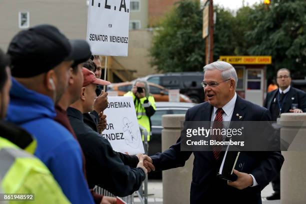 Senator Robert Menendez, a Democrat from New Jersey, shakes hands with organized labor supporters while arriving at federal court in Newark, New...