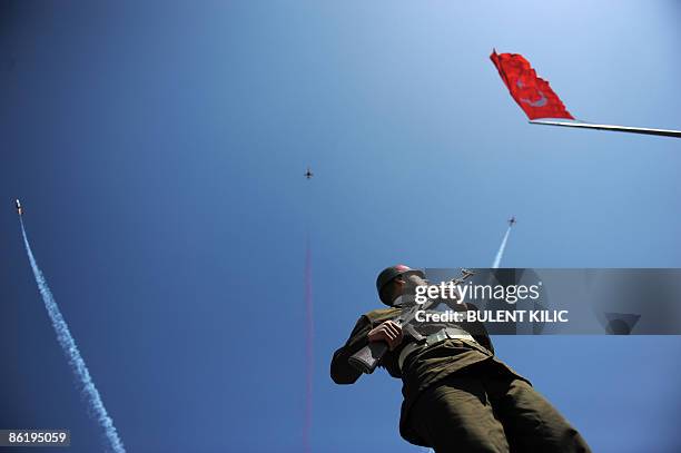 Turkish air force patrollers fly over as a Turkish soldier stands guard during the ceremony celebrating the 94th anniversary of Anzac Day in...