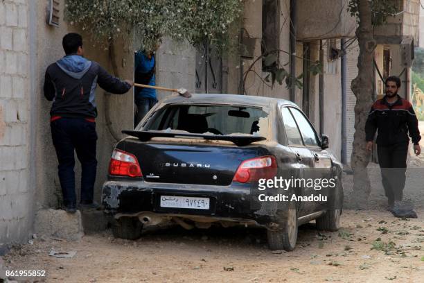 Man sweep his car after Assad regime's airstrikes hit residential areas of the de-conflict zone in Ein Tarma town of Eastern Ghouta of Damascus,...
