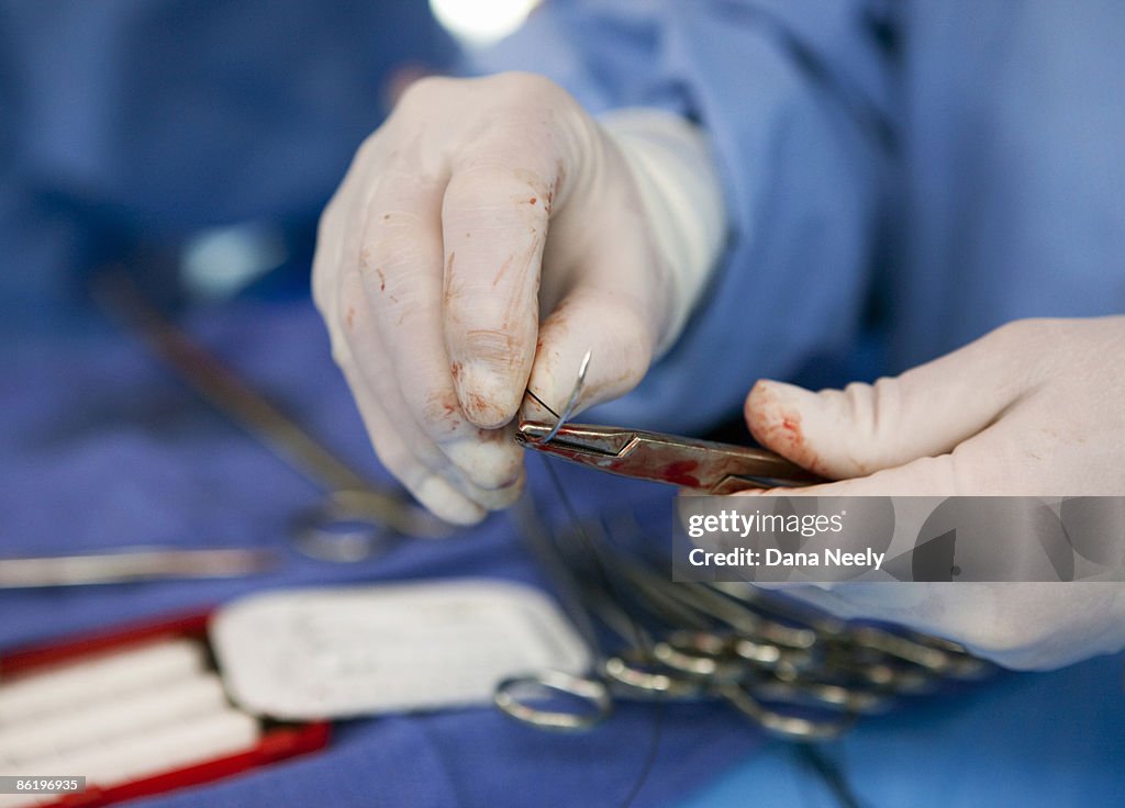 Sutures being prepared for surgeon during surgery