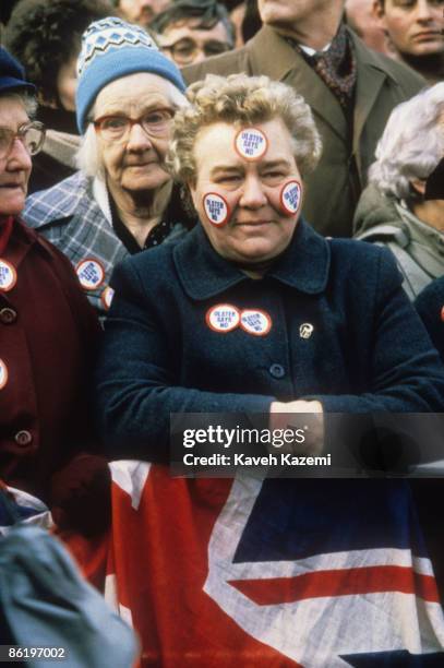 Loyalist woman, with 'Ulster Says No' stickers on her face and coat, at a demonstration outside Belfast Town Hall, 23rd November 1985. The protest is...