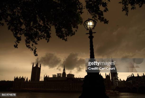 Street lamp is lit opposite the Houses of Parliament during a reddish sky caused by remnants of Hurricane Ophelia dragging in dust from the Sahara...