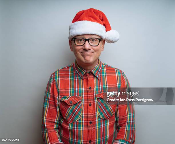 middle-aged man wearing santa hat - fotolächeln stock-fotos und bilder
