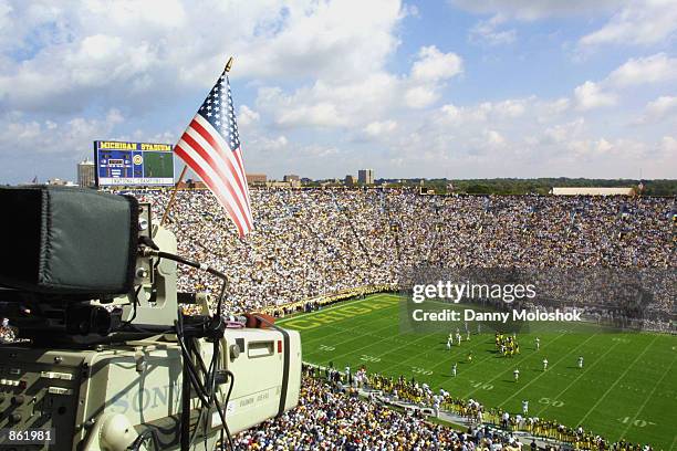 Television camera with an American Flag documents the NCAA football game between the Western Michigan Broncos and the Michigan Wolverines on...