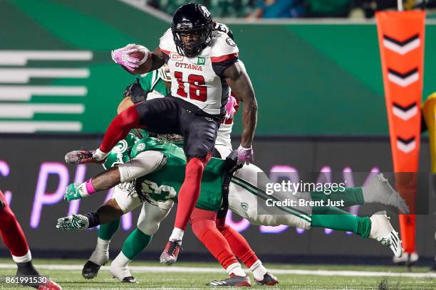 Quincy McDuffie of the Ottawa Redblacks leaps over a diving Trent Richardson of the Saskatchewan Roughriders in the game between the Ottawa Redblacks...