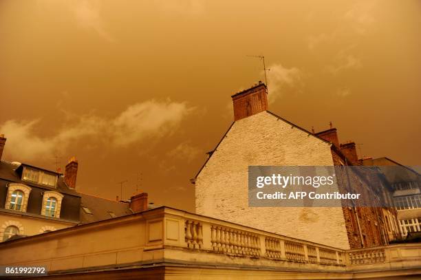 Picture taken on October 16 in central Rennes, western France, shows rooftops and the sky after it turned a yellow-ochre colour due to sand from the...