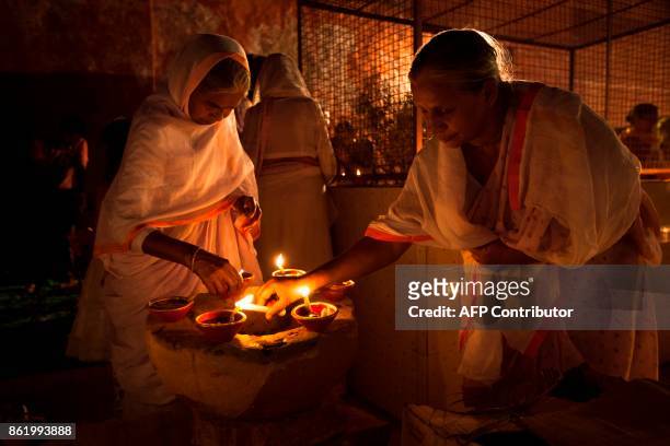Indian widows light earthen lamps or 'diyas' during Diwali celebrations at Gopinath temple in Vrindavan on October 16, 2017. Diwali, the Festival of...