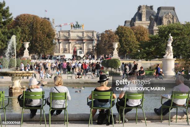 People enjoy a sunny day at the Tuileries Garden in Paris, on October 16, 2017.