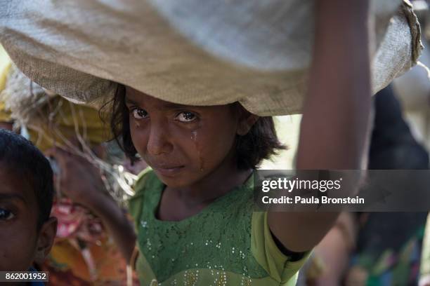 Rohingya girl cries as refugees fleeing from Myanmar cross a stream in the hot sun on a muddy rice field on October 16, 2017 near Palang Khali, Cox's...