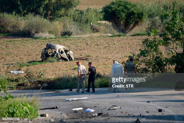 Police and forensic experts inspect the wreckage of a car bomb believed to have killed journalist and blogger Daphne Caruana Galizia close to her...