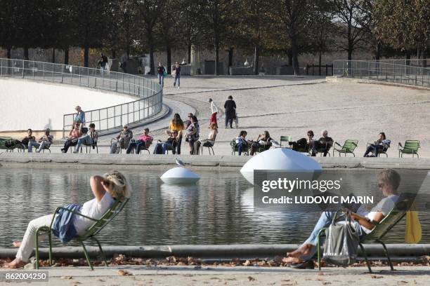 People read books and enjoy a sunny day next to the artwork "Lentilles flottantes" by Hungarian artist Marta Pan at the Tuileries Garden on October...