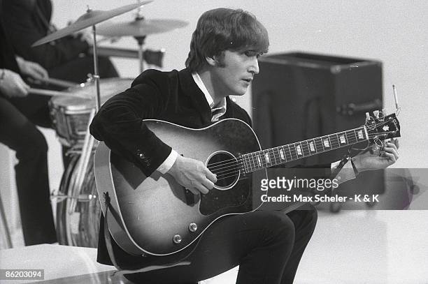 Photo of BEATLES and John LENNON; of the Beatles, tuning guitar during the filming of "A Hard Day's Night" at the Scala Theatre