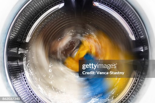 View inside the washing machine while washing laundry. Splashing water. View inside the washing machine while washing laundry. Splashing water.