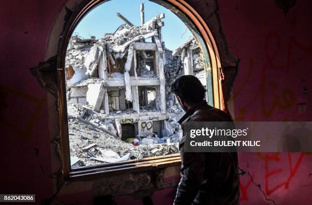 Member of the Syrian Democratic Forces , backed by US special forces, looks out from a building at the frontline in Raqa on October 16, 2017 in the...