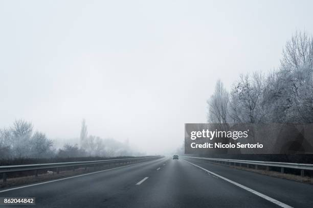 road with snow and car in distance - crash barrier stock pictures, royalty-free photos & images