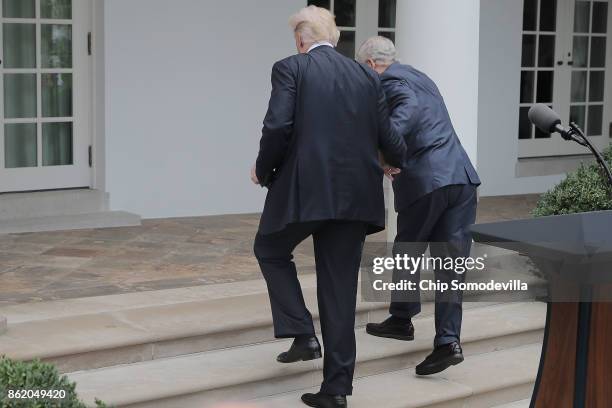 President Donald Trump lends a hand to Senate Majority Leader Mitch McConnell after he nearly tripped on the stairs leading out of the Rose Garden...