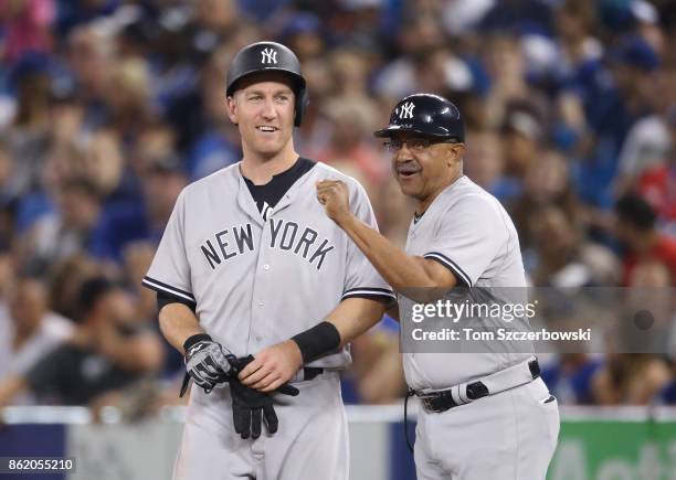 Todd Frazier of the New York Yankees shares a smile with first base coach Tony Pena after being hit by pitch in the ninth inning during MLB game...