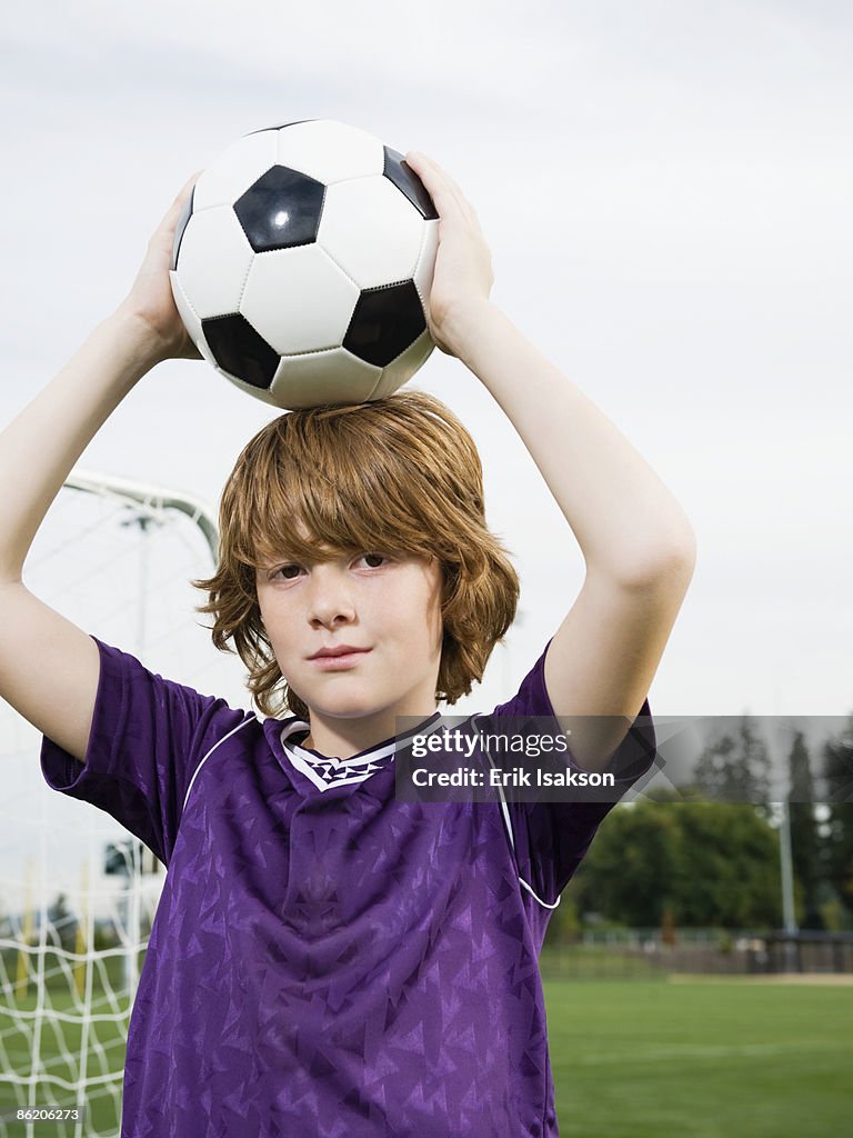 Portrait of boy holding soccer ball on head