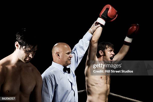 referee standing between winning and losing boxers - oficial deportivo fotografías e imágenes de stock