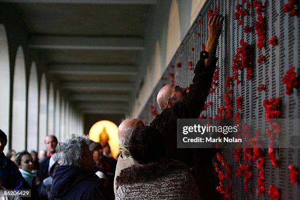 Man places a poppy on the Roll of Honour for World War II after the ANZAC dawn service at the Australian War Memorial on April 25, 2009 in Canberra,...