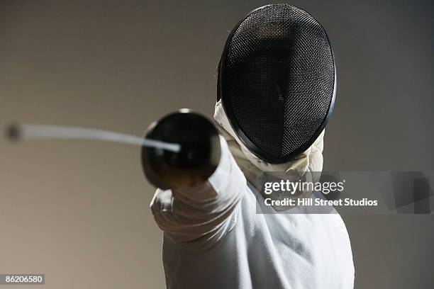 close up of fencer in mask pointing fencing foil - fioretto sport foto e immagini stock