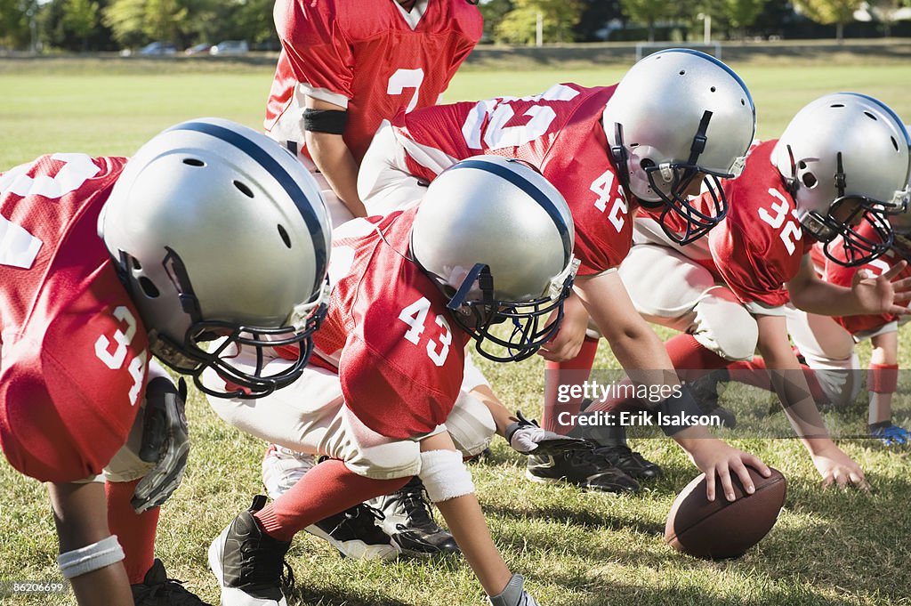Football players at line of scrimmage ready to snap football