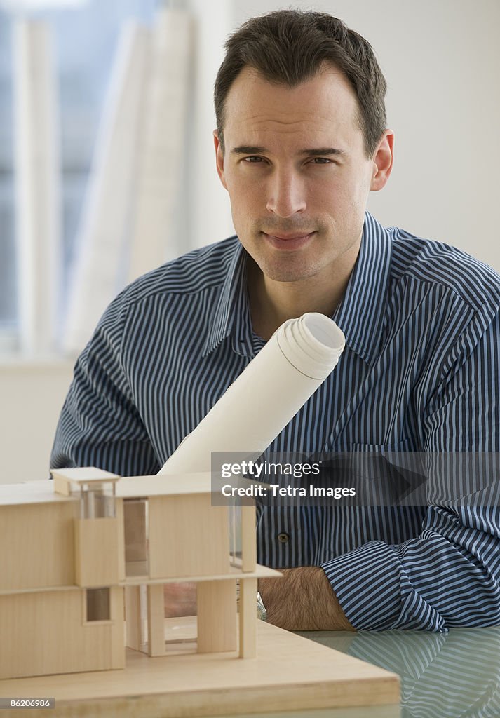 Portrait of architect with blueprints and building model