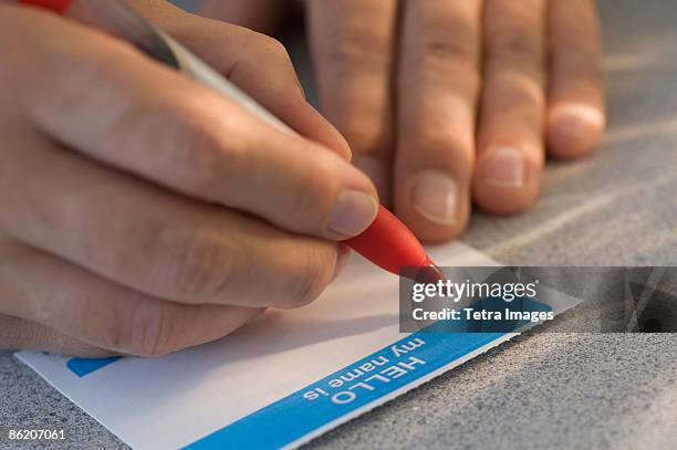 man filling out name tag - naamplaatje etiket stockfoto's en -beelden