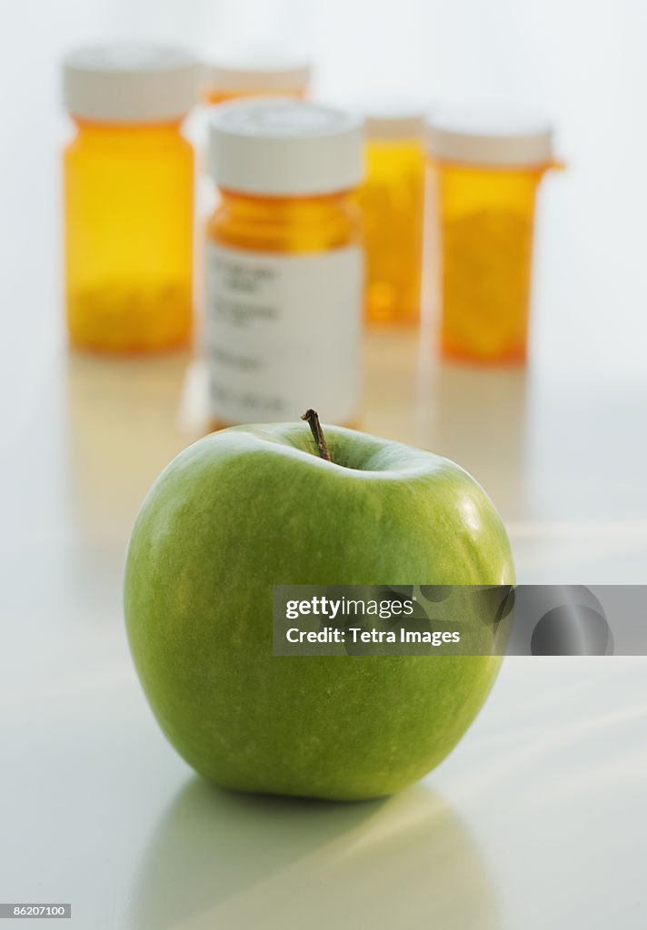 Close up of green apple with prescription bottles in background