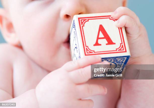 close up of baby biting on alphabet block - using mouth stock pictures, royalty-free photos & images