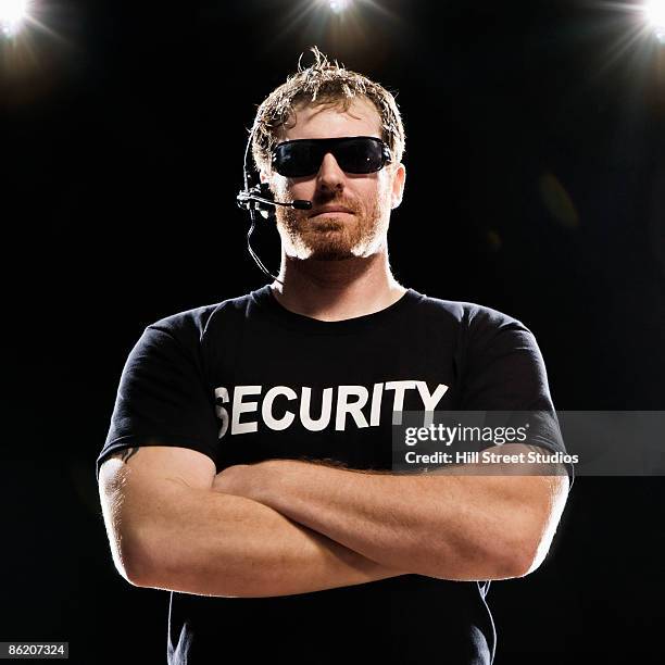 security guard with headset posing with arms crossed - agent de sécurité photos et images de collection