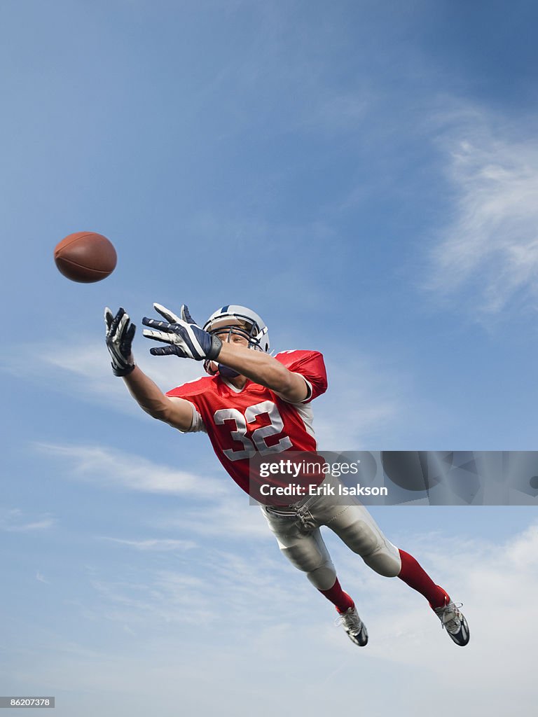 Football player in mid-air reaching for football