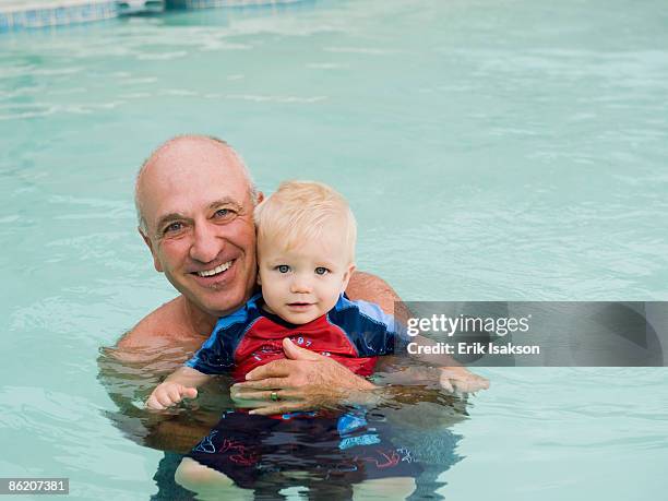 grandfather and grandson posing in swimming pool - babyschwimmen stock-fotos und bilder