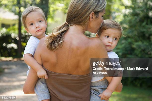 mother carrying twin toddler sons - twin boys stock pictures, royalty-free photos & images