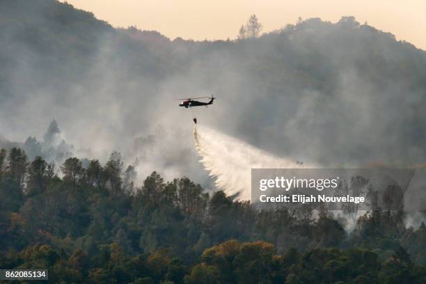 Tanker helicopter drops water on a wildfire on October 16, 2017 in Oakville, California. At least 40 people were killed with many are still missing,...