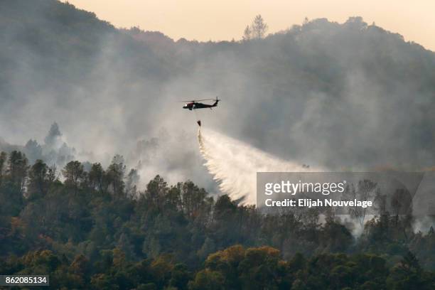 Tanker helicopter drops water on a wildfire on October 16, 2017 in Oakville, California. At least 40 people were killed with many are still missing,...
