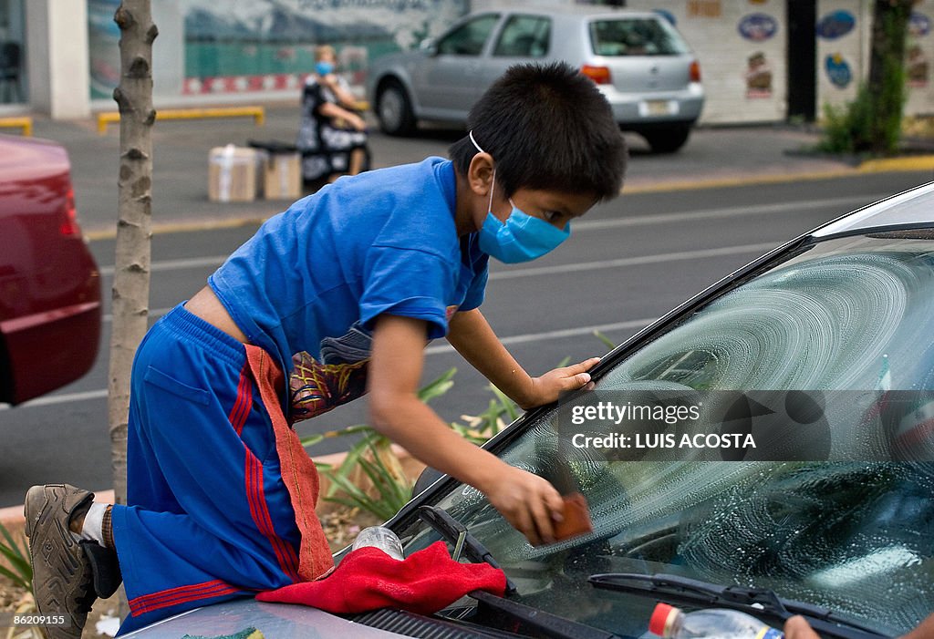 A boy cleans a car wearing a face mask a