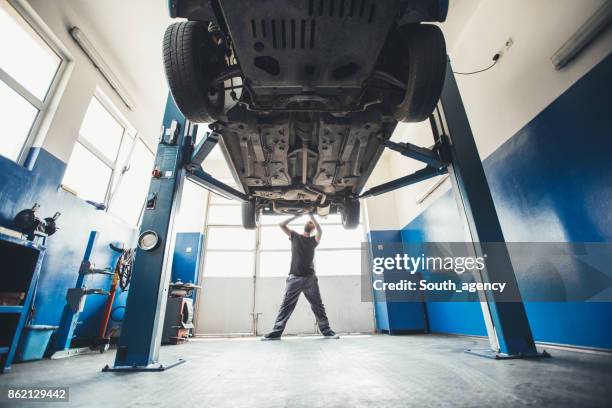 mechanic working on a car indoors - car jack stock pictures, royalty-free photos & images