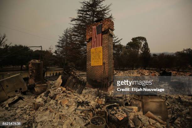 An American flag and a handmade anti-looter sign are seen on a chimney in the remains of a home on October 16, 2017 in Glen Ellen, California. At...