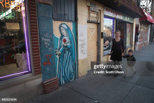 Gang graffiti is scribbled next to a mural depicting Mary, the mother of Jesus, along a strip of storefronts in the predominately Hispanic Pilsen...