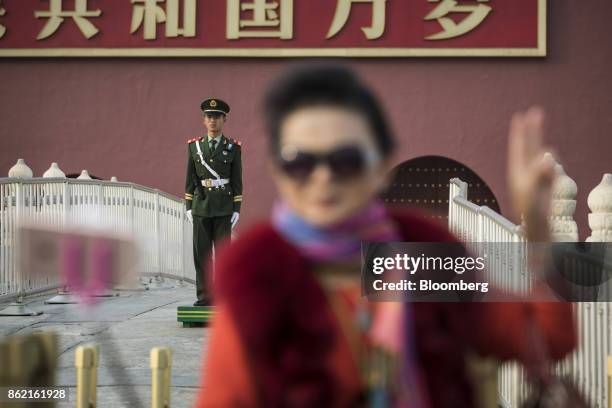Visitor poses for a photograph while a member of the Chinese People's Liberation Army stands guard at Tiananmen Square in Beijing, China on Monday,...