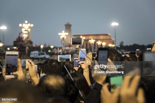 Visitors use smartphones to take photographs and video a flag lowering ceremony at Tiananmen Square in Beijing, China on Monday, Oct 16, 2017....