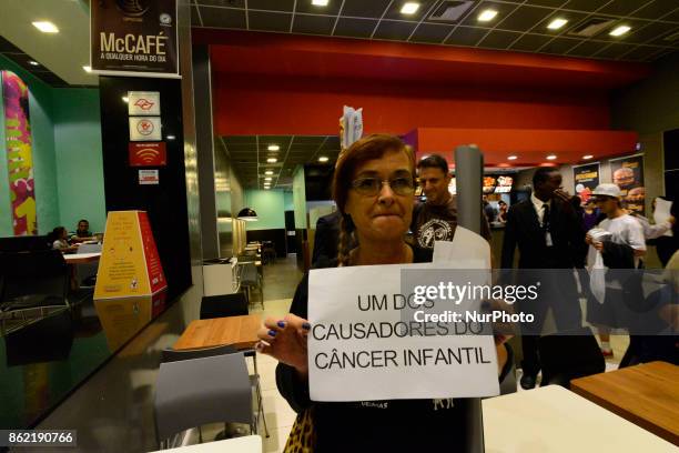 Protesters wave placards and leaflets during an animal rights march outsideand inside McDonald's restaurant on São Paulo on October 17, 2017....