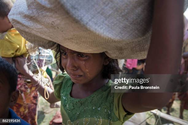 Rohingya girl cries as refugees flee from Myanmar cross a stream in the hot sun on a muddy rice field near Palang Khali, Cox's Bazar, Bangladesh....