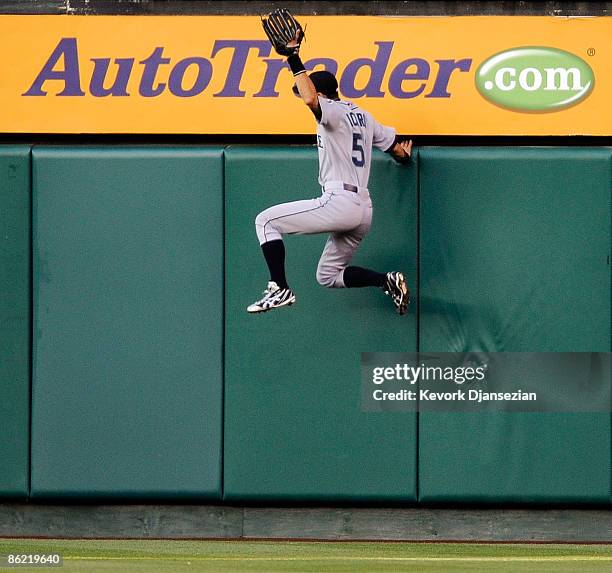 Ichiro Suzuki of the Seattle Mariners climbs up the right center field wall as a fan interferes with the play on a ball hit by Gary Matthews Jr. #24...