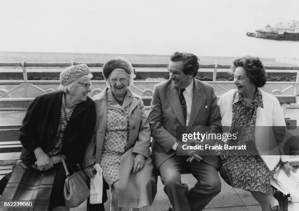 British politician Denis Healey , the Chancellor of the Exchequer, and his wife Edna chat to two ladies on the seafront at Brighton during the Labour...