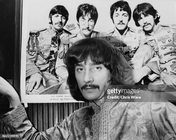 Radio 1 disc jockey Stuart Henry in front of a publicity photo of his idols, The Beatles, from the album 'Sgt. Pepper's Lonely Hearts Club Band',...