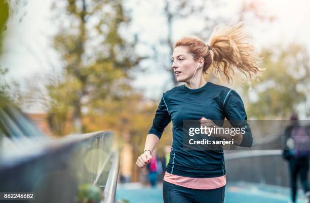 mujer atleta corriendo al aire libre - women running fotografías e imágenes de stock